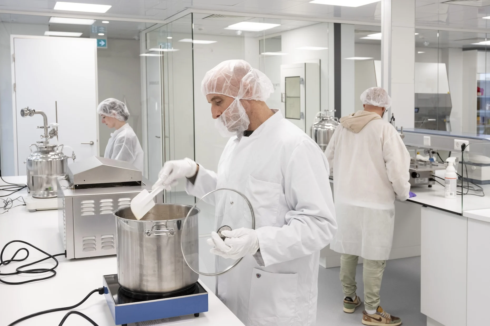 Apotheker roert in een roestvrijstalen pot tijdens medicijnbereiding